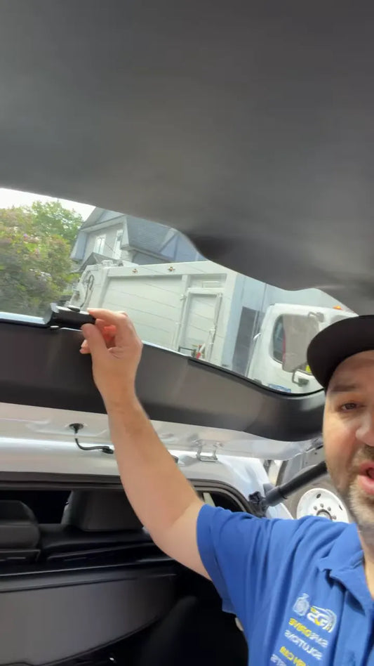 Rear dash camera mounted on the rear hatch glass with a hand adjusting its angle