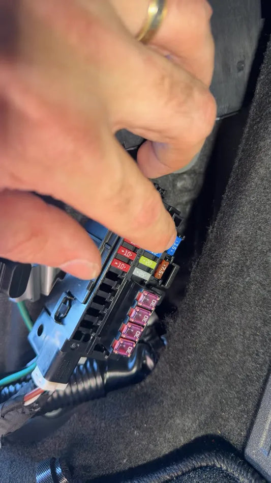 Hands working near the 2026 Mazda CX-5 fuse box connectors for dash cam hardwiring