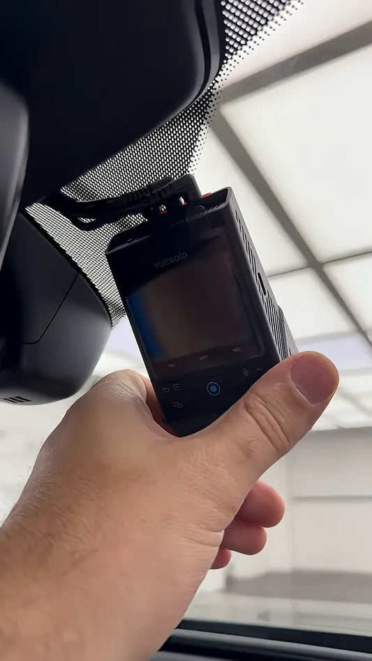 Dash camera held behind the rearview mirror with cable routed above it